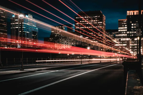 Red light trails cross a city street at night.